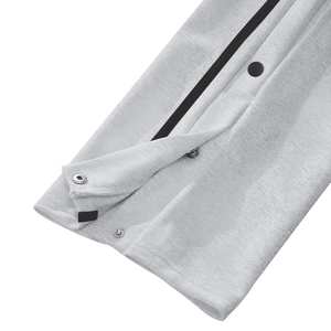 Detail of light gray joggers featuring black decorative webbing and a metal snap button