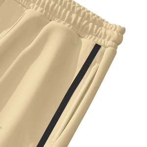 Detail of wide elastic waistband and side stripes on beige retro straight trousers