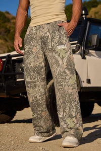 Dettaglio dei pantaloni jogger mimetici a foglia con logo bianco sulla gamba