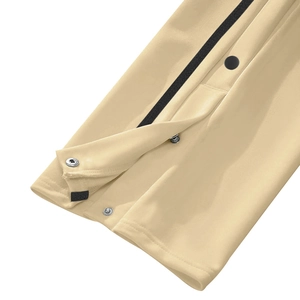 Detailed close-up of beige athletic pants leg featuring black side tape and metal snap buttons