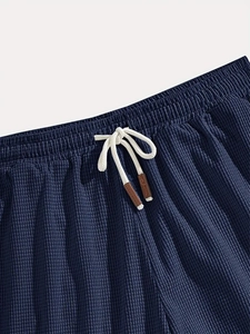 Detail of dark blue waffle texture fabric with elastic waistband and leather cord ends