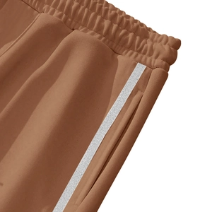 Detail view of brown casual joggers with white side stripes and elastic waistband