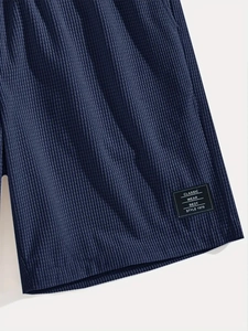 Detailed view of navy blue waffle knit fabric and classic square woven label on shorts