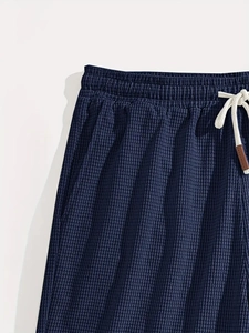 Detail of waffle textured shorts featuring elastic waistband and contrast drawstrings