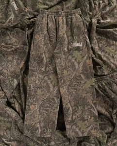 Dettaglio dei pantaloni sportivi mimetici con vita elastica e stampa del logo bianco
