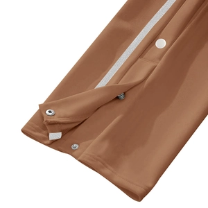 Detail view of brown joggers featuring white side stripes and silver metal snap buttons