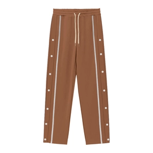 Detail of brown joggers featuring white drawstring and silver side snap button stripes