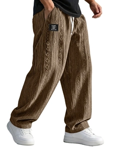 Detail view of brown corduroy joggers with jacquard patterns and decorative logo patch