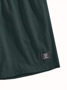 Macro shot of dark green waffle texture fabric with a classic style patch on the hem