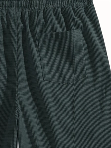 Close-up of waffle texture fabric and elastic waistband on dark green casual shorts