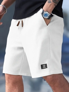 Detail of white waffle knit texture and black woven patch on men's casual shorts