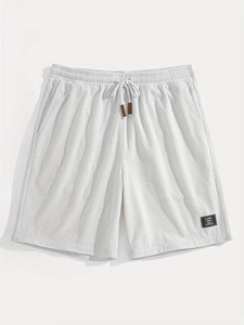 Detail of men's white waffle knit shorts showing elastic waistband and leather cord tips