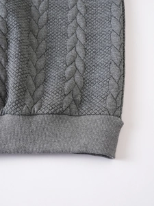 Vue détaillée du motif en maille torsadée gris foncé et de l'ourlet côtelé du pull