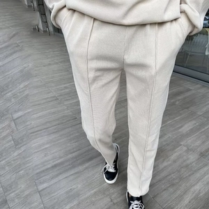 Detail of cream waffle knit trousers featuring front seams and side slit at the hemline