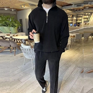 Close-up of black corduroy tracksuit showing half-zip stand collar and ribbed fabric texture
