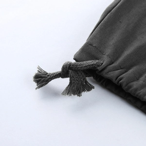 Détail macro du pantalon cargo gris foncé montrant le cordon de serrage avec des franges