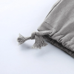 Détail macro du cordon de serrage et de la texture sergée du pantalon cargo gris