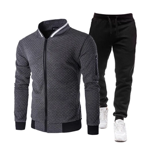 Detalle de chaqueta acolchada gris con cuello alto y pantalones de chándal negros para hombre