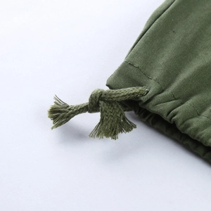 Détail macro du pantalon cargo vert olive montrant le cordon de serrage au bas des jambes