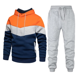 Detail view of men's tracksuit featuring orange, grey, and navy color-blocking design
