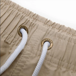 Macro shot of khaki quick-dry shorts waistband with fitness metal eyelets and drawstring