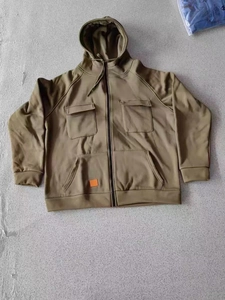 Detailed close-up of khaki utility hoodie featuring functional pockets and orange logo patch