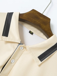 Close-up of beige polo shirt collar with black contrast stripes and two white buttons