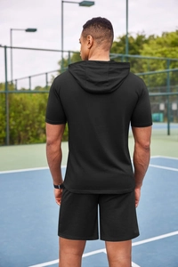 Vue arrière d'un ensemble de survêtement noir à manches courtes pour hommes sur un court de tennis