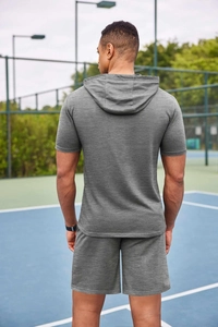 Vue arrière d'un homme en ensemble t-shirt à capuche et short gris foncé sur un court