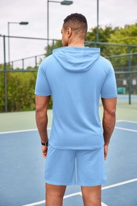Survêtement homme bleu ciel à manches courtes et capuche sur un terrain de tennis