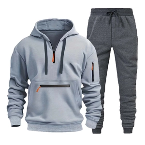 Dettaglio felpa con cappuccio azzurra con accenti arancioni e pantaloni sportivi grigi