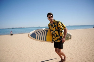 Detailed view of lightweight men's banana print beach shirt with a surfboard