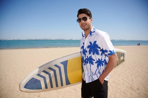Detail of men's tropical palm tree print short sleeve shirt on a sunny beach