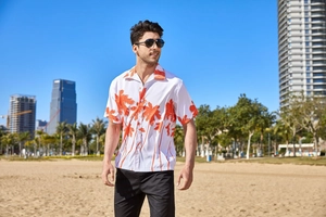 Detail shot of men's white Hawaiian shirt featuring vibrant orange palm tree prints