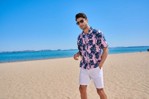 Detail of pink Hawaiian shirt with blue palm prints and white shorts for beach vacation