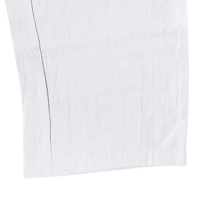 Vista detallada del bajo de pantalón de lino blanco con costuras y tejido transpirable