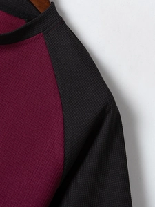 Dettaglio del tessuto a nido d'ape bordeaux con manica raglan e colletto nero