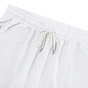 Detalle del pantalón de lino blanco con cintura elástica, cordón trenzado y puntas metálicas