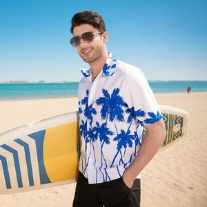 Men's Hawaiian short sleeve shirt with navy palm tree prints on beach with surfboard