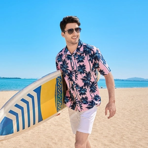 Men's pink tropical short sleeve shirt with navy palm tree print on a sunny beach