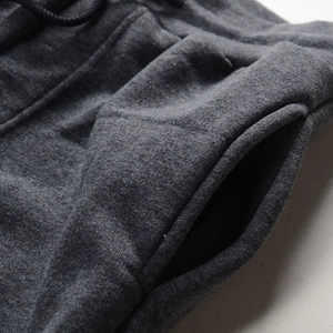 Detail view of dark grey joggers featuring waist drawstring and side slash pockets texture