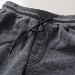 Detail of grey sweatpants featuring elastic waistband with black adjustable drawstrings