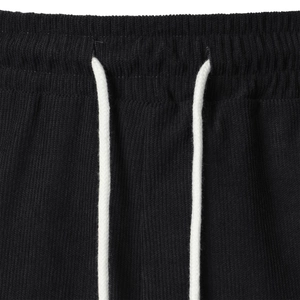 Detail of black corduroy shorts featuring elastic waistband and white contrast drawstring