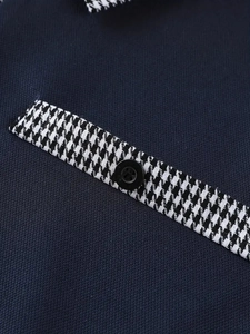 Dettaglio macro della polo blu navy con finitura pied de poule e bottone nero opaco
