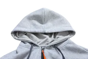 Detailed close-up of grey zip-up hoodie featuring a zipper with orange cord detail
