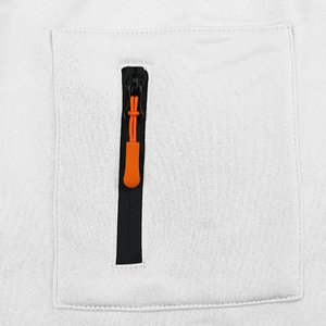 Détail d'un pantalon cargo blanc montrant une poche zippée avec tirette orange