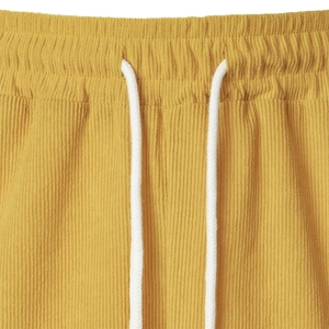 Detailed macro view of yellow corduroy fabric with elastic waistband and white drawstring
