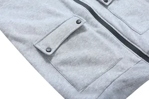 Close-up of light gray hoodie fabric with metal snap pockets and durable resin zipper
