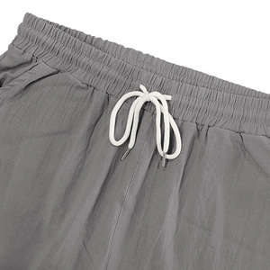 Detalle de pantalones de lino gris para hombre con cintura elástica y cordones blancos