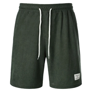 Detail of dark green corduroy shorts with elastic drawstring waist and sports textile label